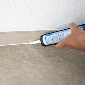 Silikonspritze mit neu gezogener Silikonfuge an Sockelleiste