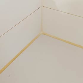 Vergilbte weiße Silikonfuge in einer Dusche