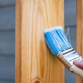 Pinsel beim Imprägnieren eines Zauns